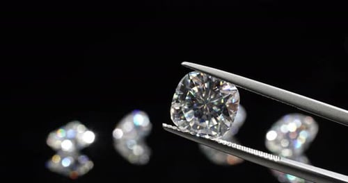 Tweezers Hold a Cushion-Cut Diamond over Gems