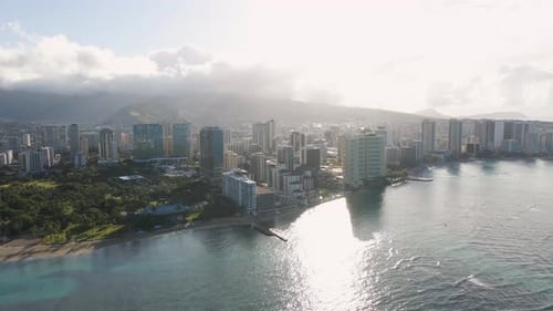 Metropolitan city on the beach of a tropical island with mountains in the background at sunrise