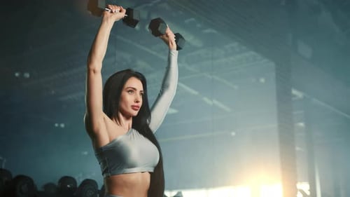 Medium Close Up of Attractive Woman Performing Dumbbell Shoulder Press in Gym