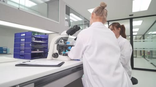 Scientists Analyzing Samples Using Microscope in Bright Lab
