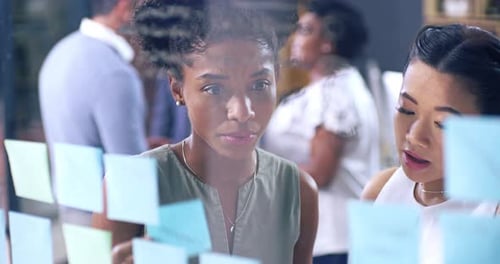 Women Collaborating, Writing Ideas on Glass Wall