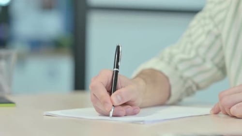 Nahaufnahme eines jungen Mannes, der im Büro schreibt