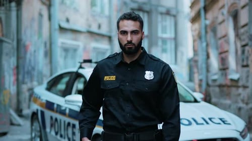 Serious Police Officer with Handgun Stands Guard