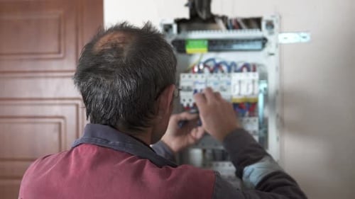 An electrician assembles a switchboard in a new building apartment.