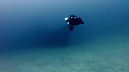 Solo Technical Scuba Diver Exploring Deep Blue Mediterranean Waters Above Sandy Seabed Near Comino