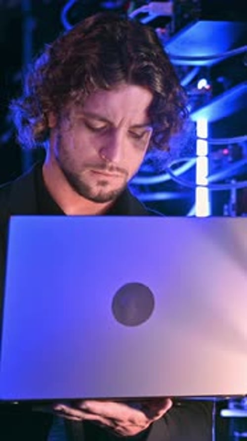 Man Works on Laptop in Data Center