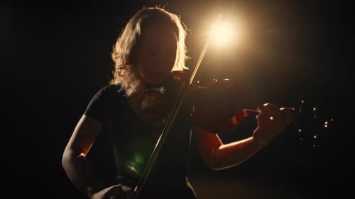 Woman Plays Violin in Dramatic Spotlight