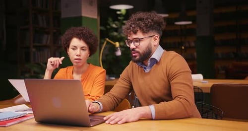 Professional Colleagues Analyzing Documents Using Laptop Working in Modern Office Sitting on Table