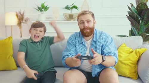 Father and son play video games on couch