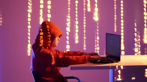 Hacker en sweat à capuche rouge codant dans une pièce sombre avec projection de code binaire sur le mur et les bras