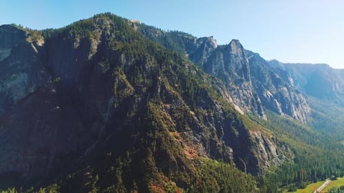 Pine trees covering the sunny side of huge rocks. Stunning mountains in Yosemite National Park