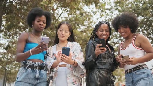 Cheerful Transgender Woman and Female Friends Using the Mobile in a Park