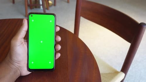 Hand Holding Smartphone with Blank Screen in Cafe