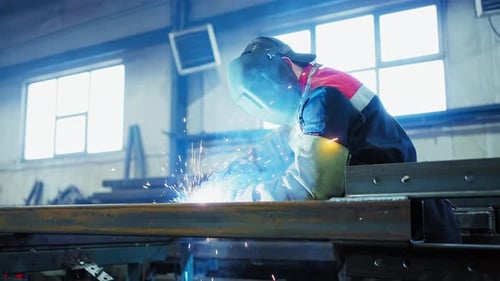 Professional Welder Working at Factory Facility Factory Workshop with a Male Technician Welding in