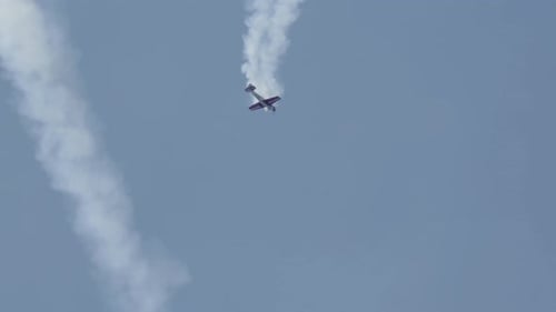 Stunt plane in a stalled spiral with smoke trail.