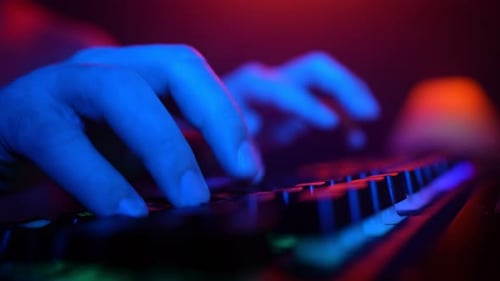 Männliche Hände tippen bei Neonbeleuchtung auf Computertastatur Hacker und Cyberkriminalität