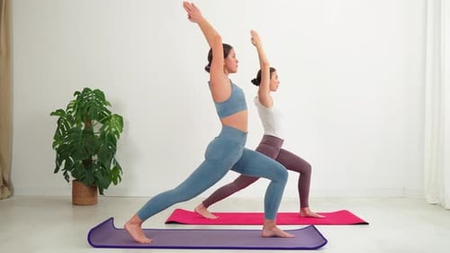 Young Adults Practicing Yoga Exercise Indoors on Yoga Mats