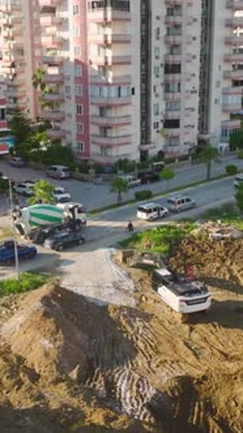 Vídeo vertical: sitio de construcción ocupado con máquinas pesadas y constructores activos