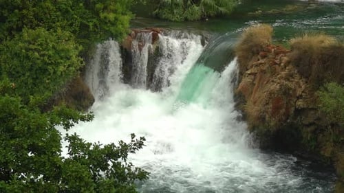 Large waterfall pouring from one pond to another blue pond in Krka National Park in Croatia at ¼ spe