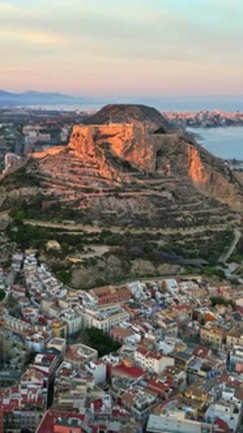 Aerial drone view of the Santa Barbara Castle surrounded by buildings on the coast of Alicante, Spai
