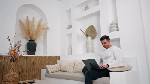 Man Working on Laptop in Bright White Home