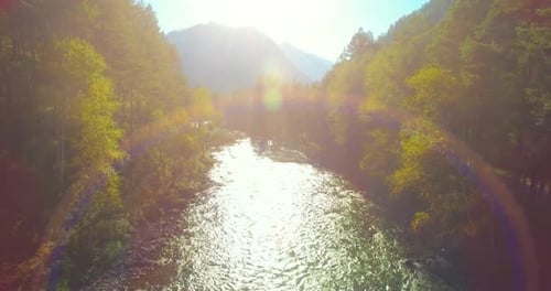Flug in niedriger Höhe über einen frischen, schnellen Gebirgsfluss mit Felsen an einem sonnigen Sommermorgen