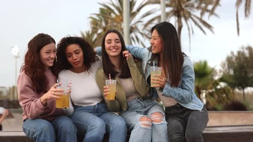 group of multiracial friends having refreshments together on the beach