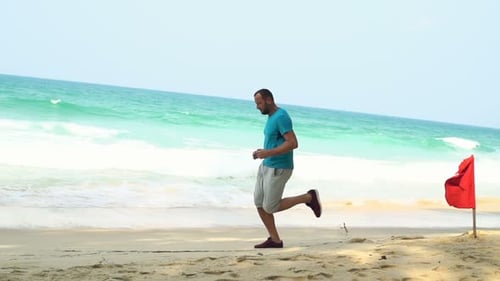 Young man jogging on tropical beach in super slow motion seaside exercise