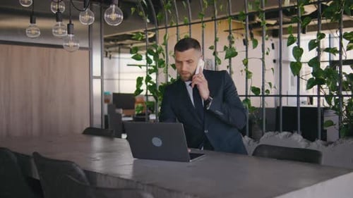 Male Businessman Working in a Modern Office at a Laptop and Calls on the Phone Portrait of a Male
