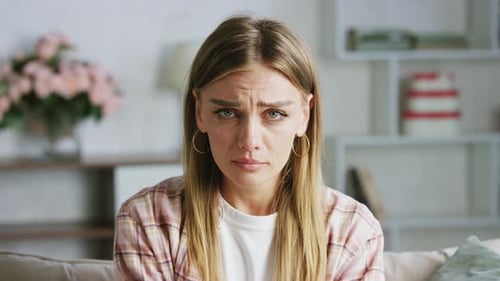 Young woman sitting on couch is crying suffering from depression