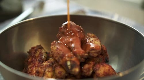 Pouring hot sauce on chargrilled chicken wings