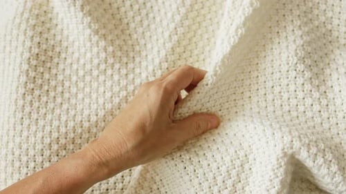 Woman's Hand Touching Cream Knitted Blanket Texture