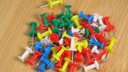 Colorful push pins rotating on the desk. Drawing pins for marking on the map of the Earth or city
