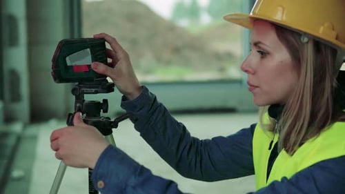Junge Arbeiterin mit Laser auf der Baustelle