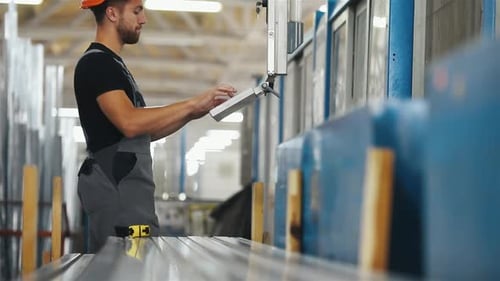 Operator indoors in the factory use special machine to type a data