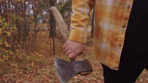 A Man Menacingly Walks Through the Autumn Forest with an Axe