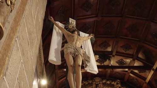 Crucifix of Jesus Christ mounted on a stone wall inside a church, under soft lighting