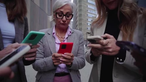 Businesswomen Using Phones Outside City Building