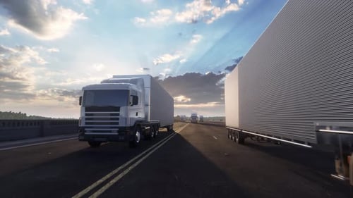Convoy Of White Semi Trucks On Highway At Sunset