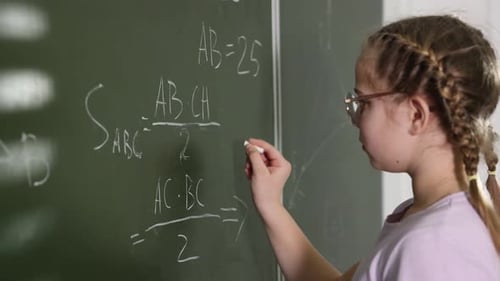 Girl Writing Math Equations on Chalkboard in Classroom
