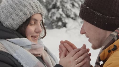 Loving Couple Warming Hands in Winter Forest