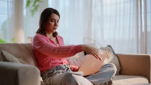 Woman Working on Laptop Relaxing on Sofa