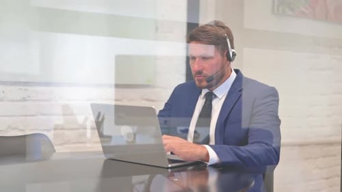 Middle Aged Businessman with Headset Working on Laptop in Call Center