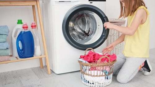 Kleines Mädchen lädt Kleidung in die Waschmaschine