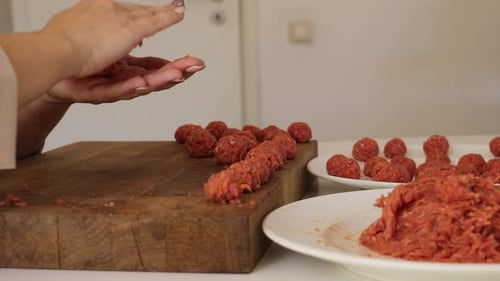 A woman works diligently in her kitchen, preparing delicious meatballs.