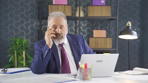 Businessman Answering Phone at Desk in Office