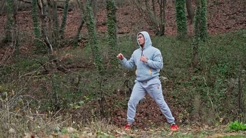 Man Performs High Kicks In Dense Forest Person Practices Rapid High Kicks Among Leafcovered Trees An