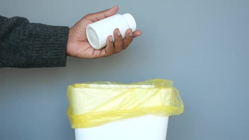 Medication Bottle Dropped Into Trash Can