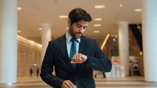 Smiling Man Checks Watch in Modern Office Building