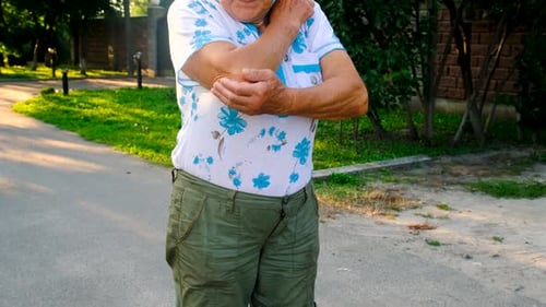Senior Woman Rubbing Her Elbow Outside